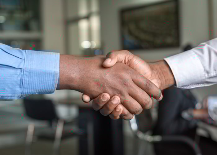 Handshake representing Hotelware Group's growth and partnerships since 1989